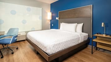 Una habitación de hotel moderna con una cama grande, un escritorio, una silla y un ventanal con vistas.