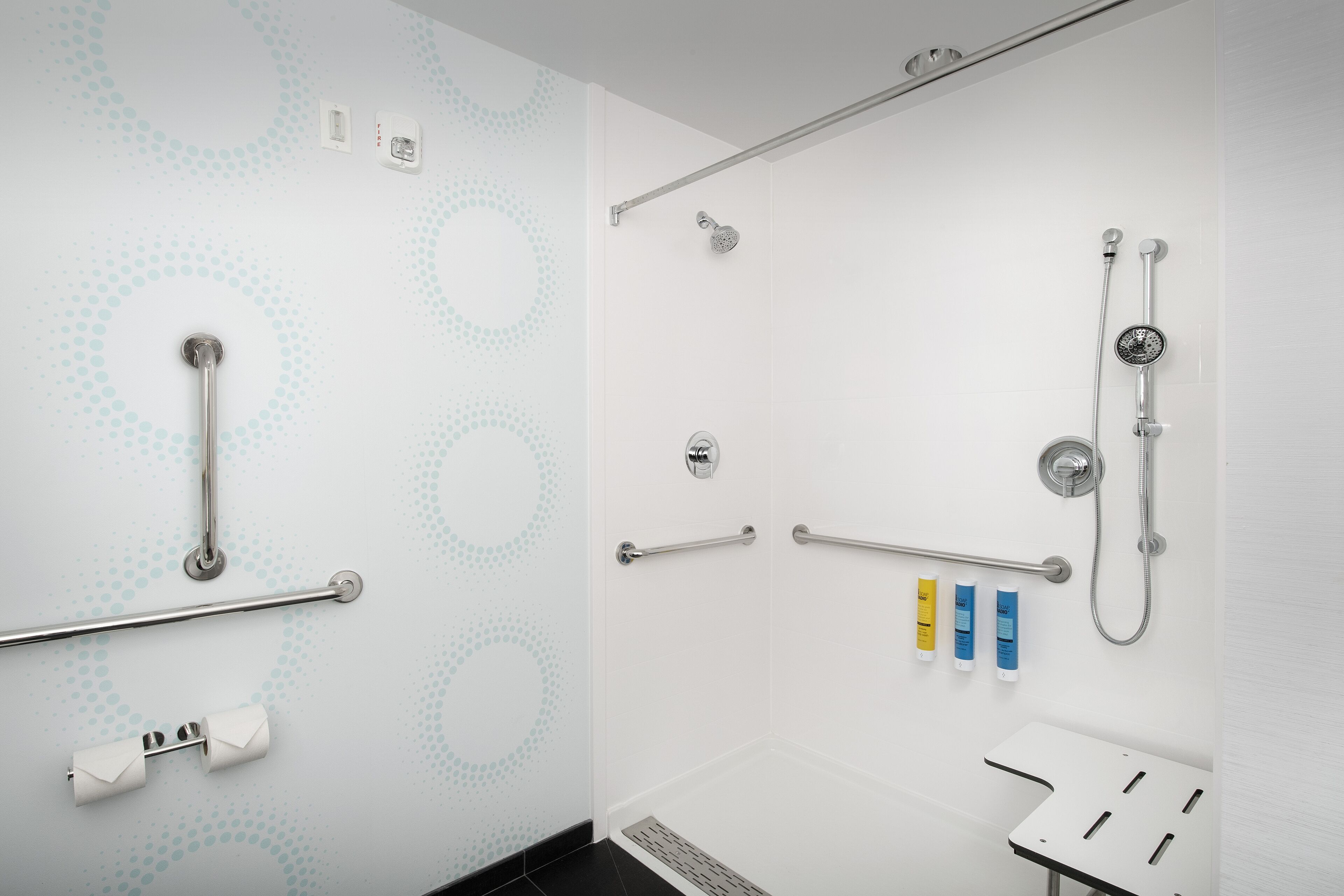 A modern bathroom with a shower, grab bars, and a toilet with a safety grab bar.