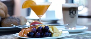 Un plato de comida con frutas y un vaso de jugo de naranja.