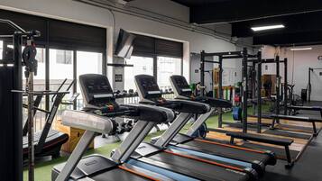 Une salle de sport équipée de tapis de course, de machines de musculation et d’un support pour les exercices de squat.