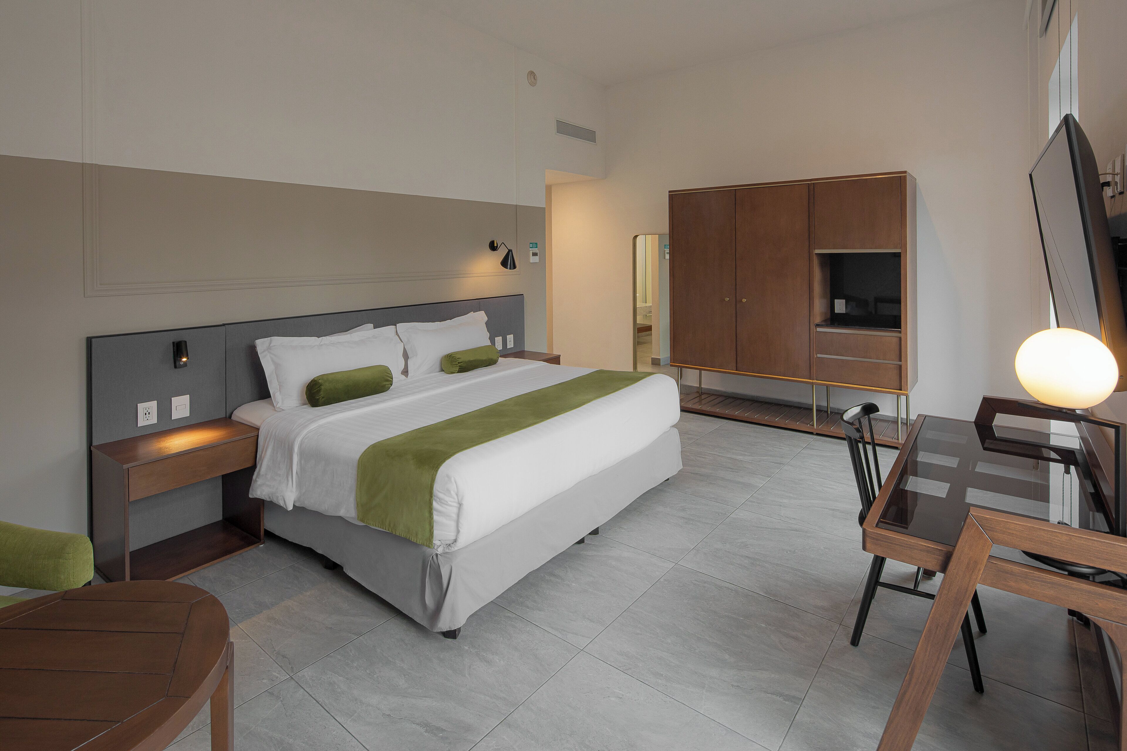 Una habitación de hotel moderna con cama, mesitas de noche, escritorio y silla.