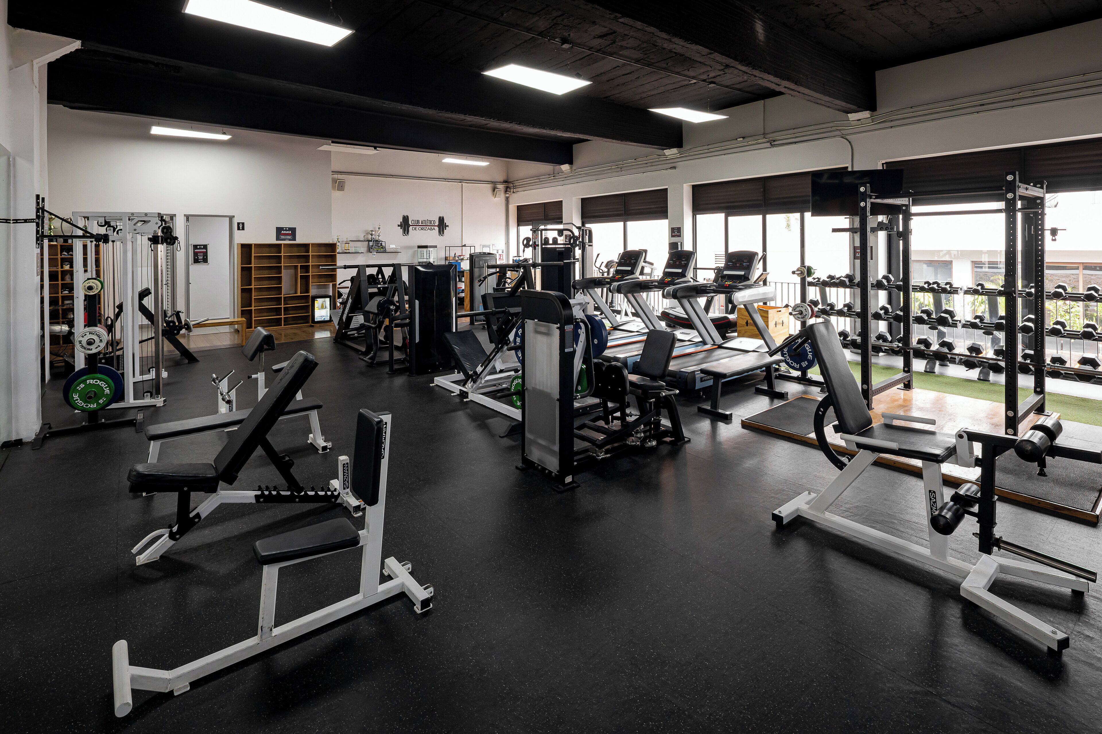 A gym with various exercise equipment, including treadmills, weight machines, and dumbbells.