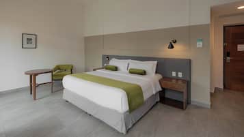 A hotel room with a bed, bedside tables, a chair, and a small table.