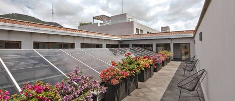 A rooftop terrace with solar panels, flower planters, and seating areas.