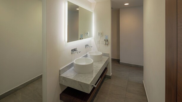 Un baño moderno con dos lavamanos, un espejo grande e iluminación empotrada.