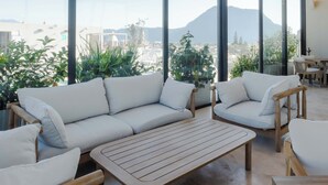 Una sala de estar moderna con un sofá grande, una mesa de centro de madera y vistas a la montaña.