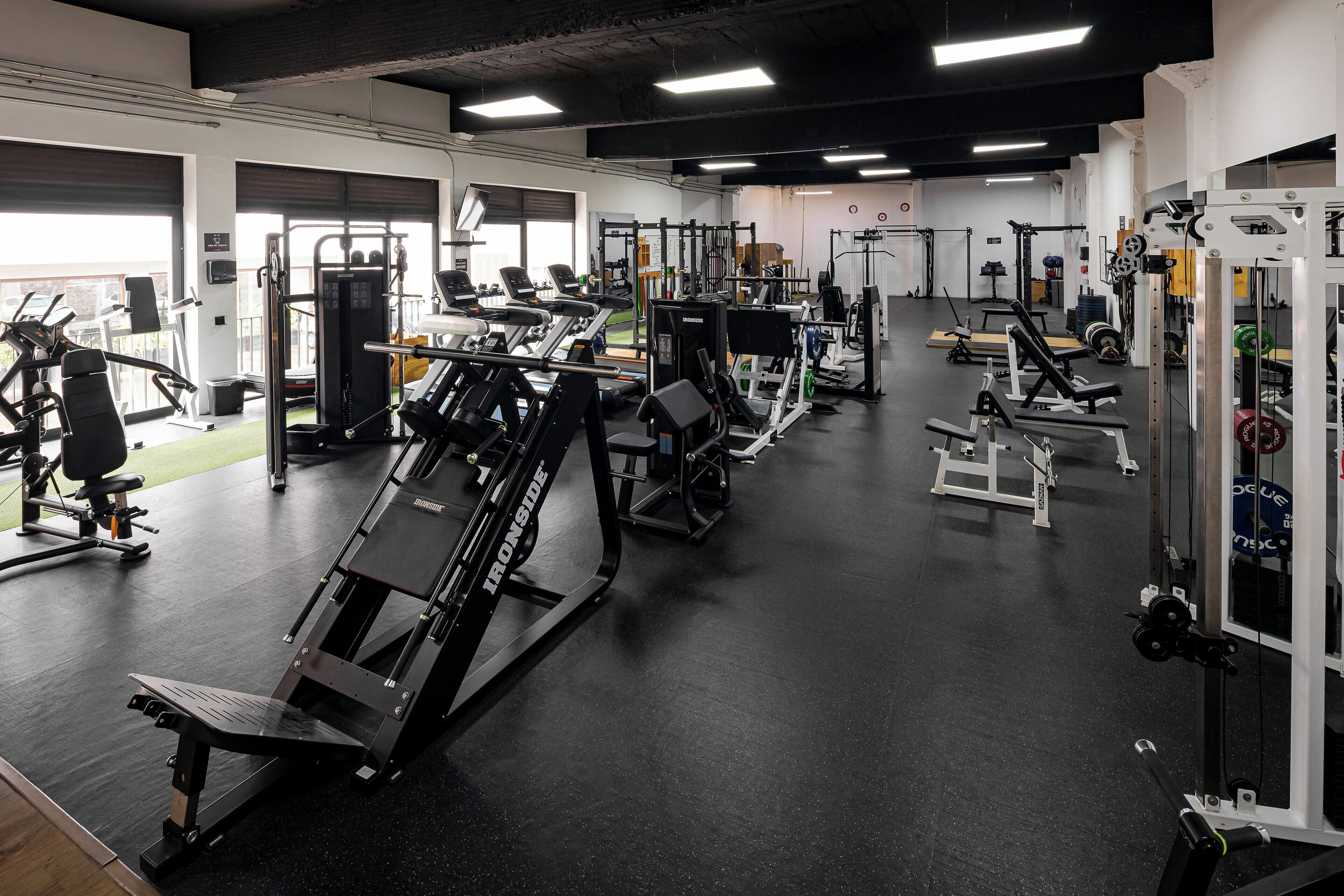 Un gimnasio con diversos equipos de ejercicio, incluyendo cintas de correr, máquinas de pesas y pesas sueltas.
