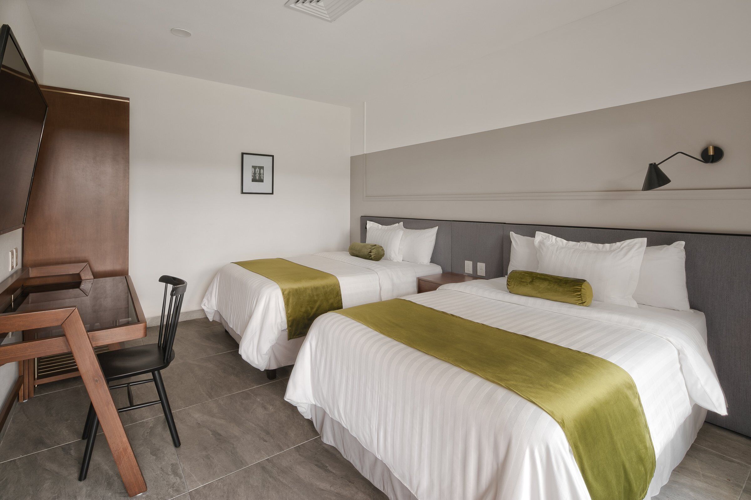 Une chambre d’hôtel avec deux lits, un bureau et une chaise.