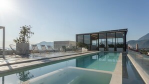 Una piscina en la azotea con sillones de descanso y una estructura de vidrio.
