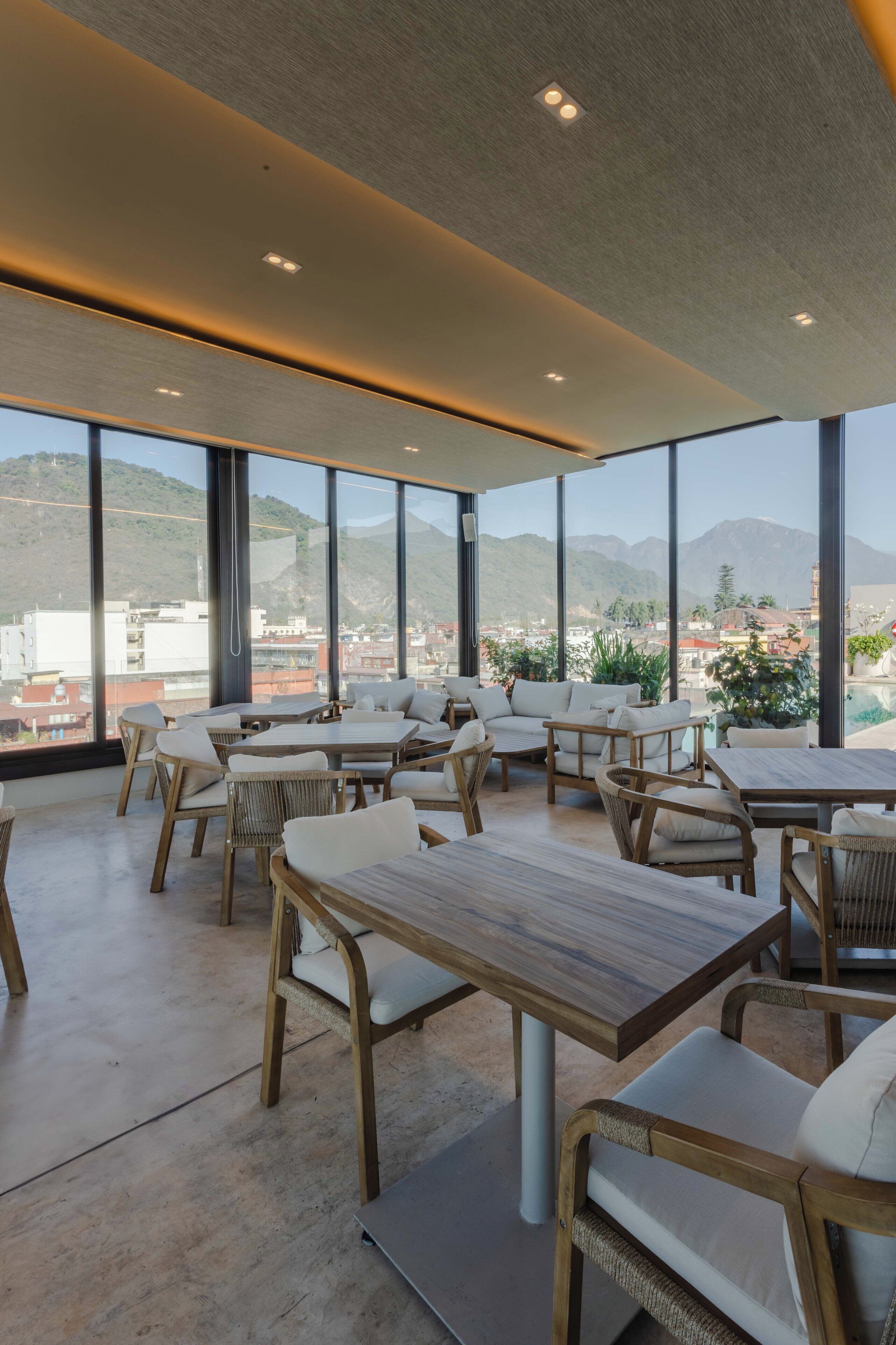 Un comedor moderno con ventanas amplias, mesas de madera y sillas de mimbre.