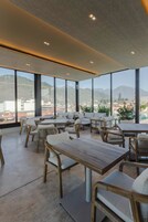 Un comedor moderno con ventanas amplias, mesas de madera y sillas de mimbre.