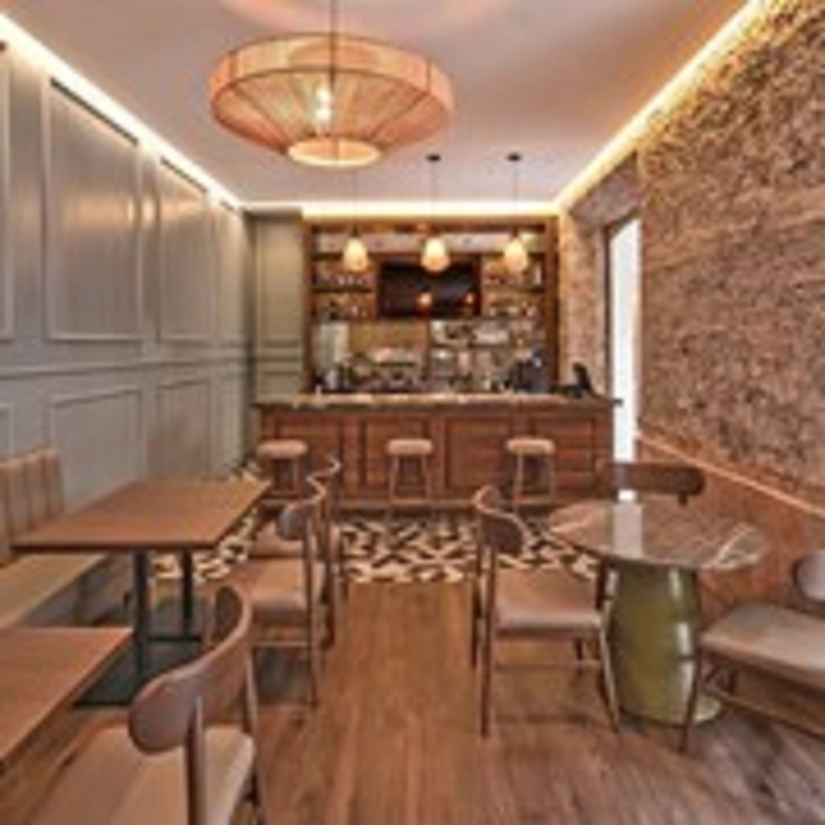 A restaurant with wooden tables and chairs, a bar area, and a stone wall.