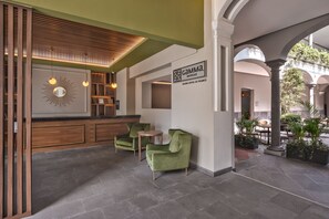 A hotel lobby with green armchairs, a wooden reception desk, and a sign for Gamma Hotels. - Gamma Orizaba Grand Hotel de France (Orizaba)