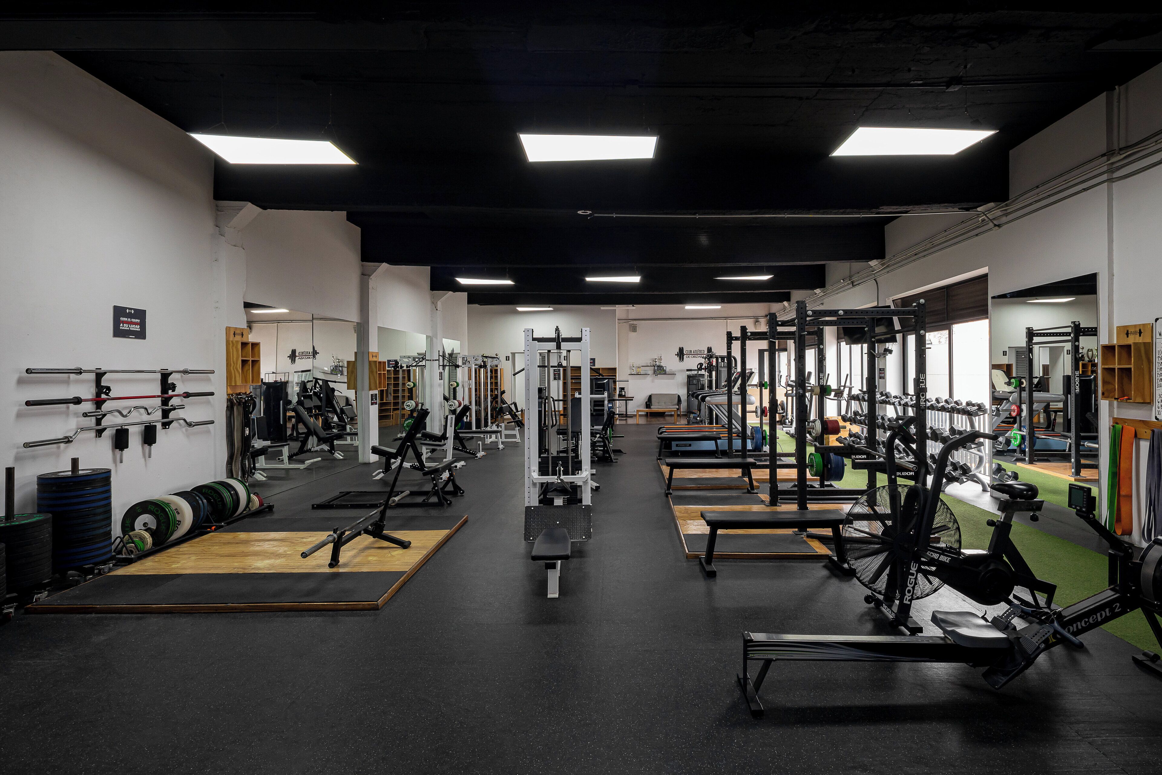 Et fitnesscenter med forskellig træningsudstyr, herunder styrkemaskiner, løbebånd og vægte.