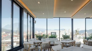 Una amplia terraza en la azotea con varias zonas de estar, grandes ventanales que ofrecen vistas panorámicas de la ciudad y un diseño de techo moderno.
