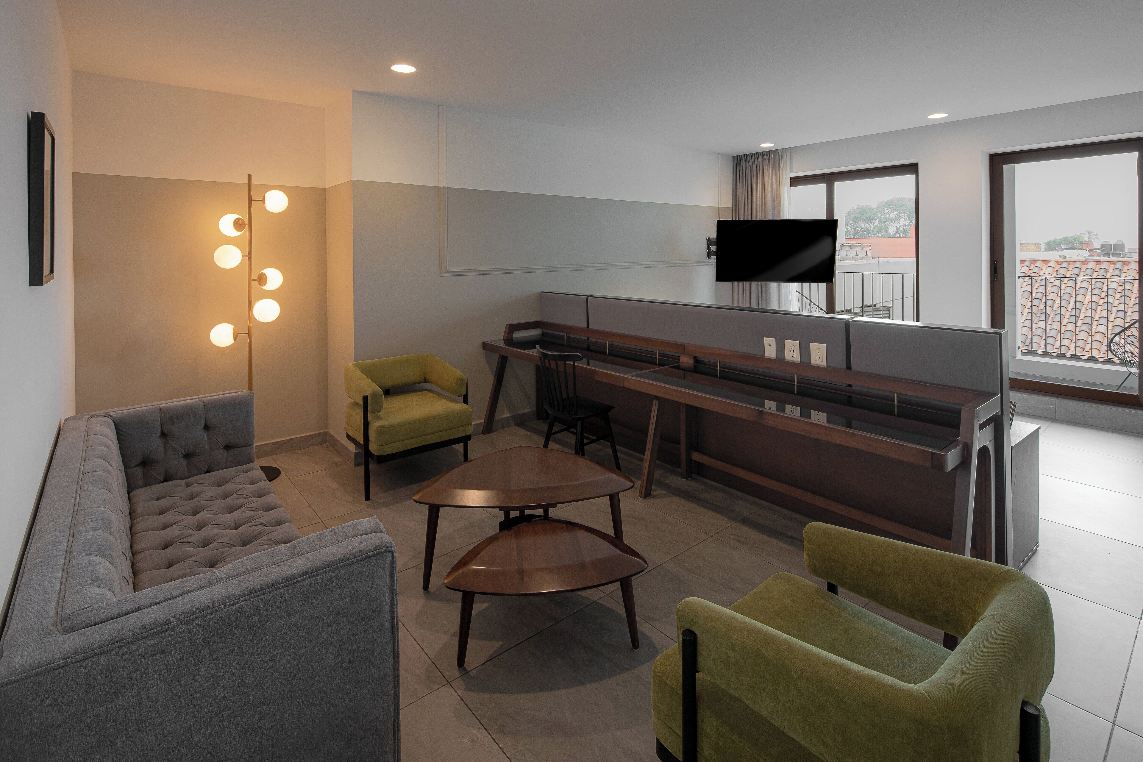 A modern living room with a sofa, chairs, a coffee table, a TV, and a bar area.