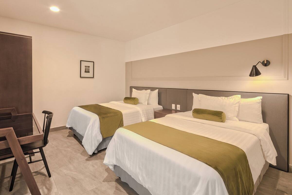 A hotel room with two beds, a desk, and a chair.