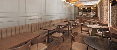 A restaurant interior with wooden tables and booths, a bar area, and pendant lighting.