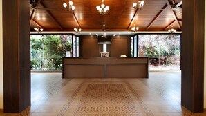Un área de recepción con techo de madera, mostrador de recepción y piso estampado.