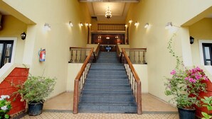 Una escalera con barandilla de madera que lleva a un rellano con candelabro.