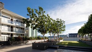 A modern building with balconies, a landscaped courtyard, and a clear sky. - Central Islington (Townsville)