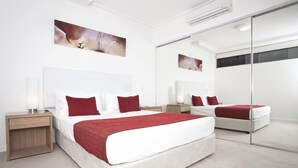 A modern hotel room with a large bed, a nightstand, a mirror, and artwork on the walls. - Central Islington (Townsville)