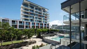 A modern hotel with a rooftop pool, multiple balconies, and a clear sky. - Central Islington (Townsville)