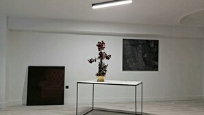 A minimalist room with a marble floor, a glass-top table with a potted plant, and two framed artworks on the walls. - The Link Athens (Athens)