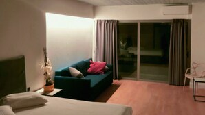A hotel room with a bed, a sofa, a small table, and a sliding glass door leading to a balcony. - The Link Athens (Athens)