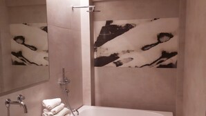 A modern bathroom with a rectangular sink, a large mirror, a white bathtub, and a wall-mounted towel rack. - The Link Athens (Athens)