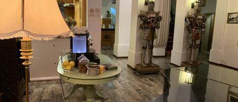 A room with a round table, a lamp, and a statue of a knight.