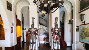 A hallway with two knight statues, a staircase, and a map on the wall. - Hotel Ficocle (Cervia)