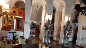 A modern interior with a polished floor, arched doorways, and a central area with a coffee machine and fruit. - Hotel Ficocle (Cervia)