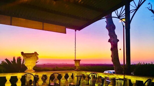 An outdoor seating area with chairs and tables, overlooking a scenic sunset view. - Hotel Ficocle (Cervia)