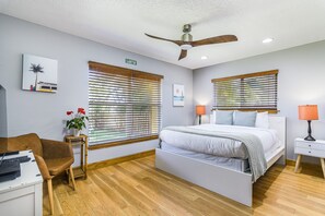 Un dormitorio con cama, escritorio, silla, ventilador de techo y ventana con persianas.