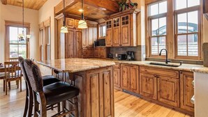 A kitchen with wooden cabinets, a granite countertop, and a bar area. - The Luxurious Lincoln Hot Tub (Breckenridge)