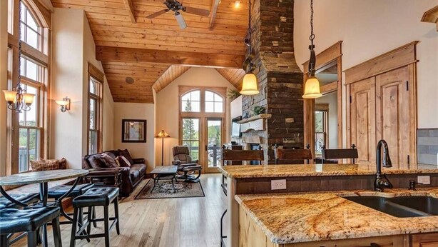 A spacious kitchen with a granite countertop, wooden cabinets, and a stone fireplace. - The Luxurious Lincoln Hot Tub (Breckenridge)