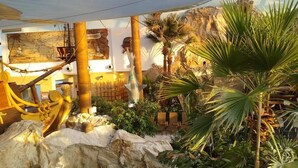An indoor tropical-themed area with a large map, palm trees, and a ship's wheel. - Holiday Home Tatralandia (Liptovsky Mikulas)