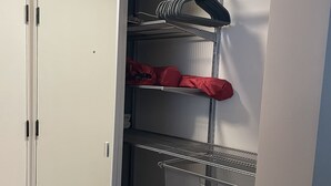 A walk-in closet with metal shelving units, a white wardrobe, and a wooden floor.