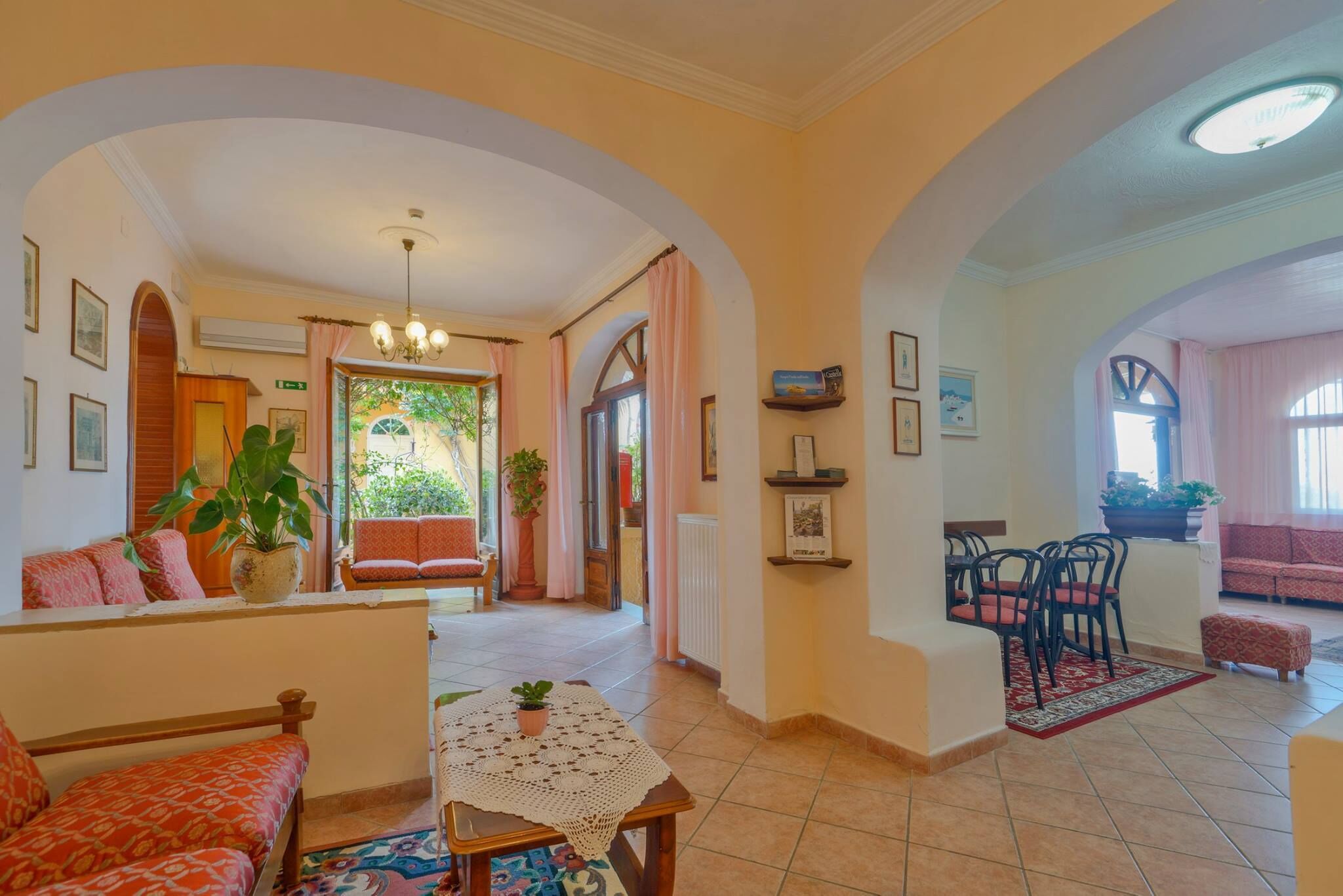 A spacious living area with a sofa, a table with a plant, and a dining area with chairs.