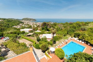 Un complexe hôtelier doté d’une piscine, de chaises longues et offrant une vue sur la mer.
