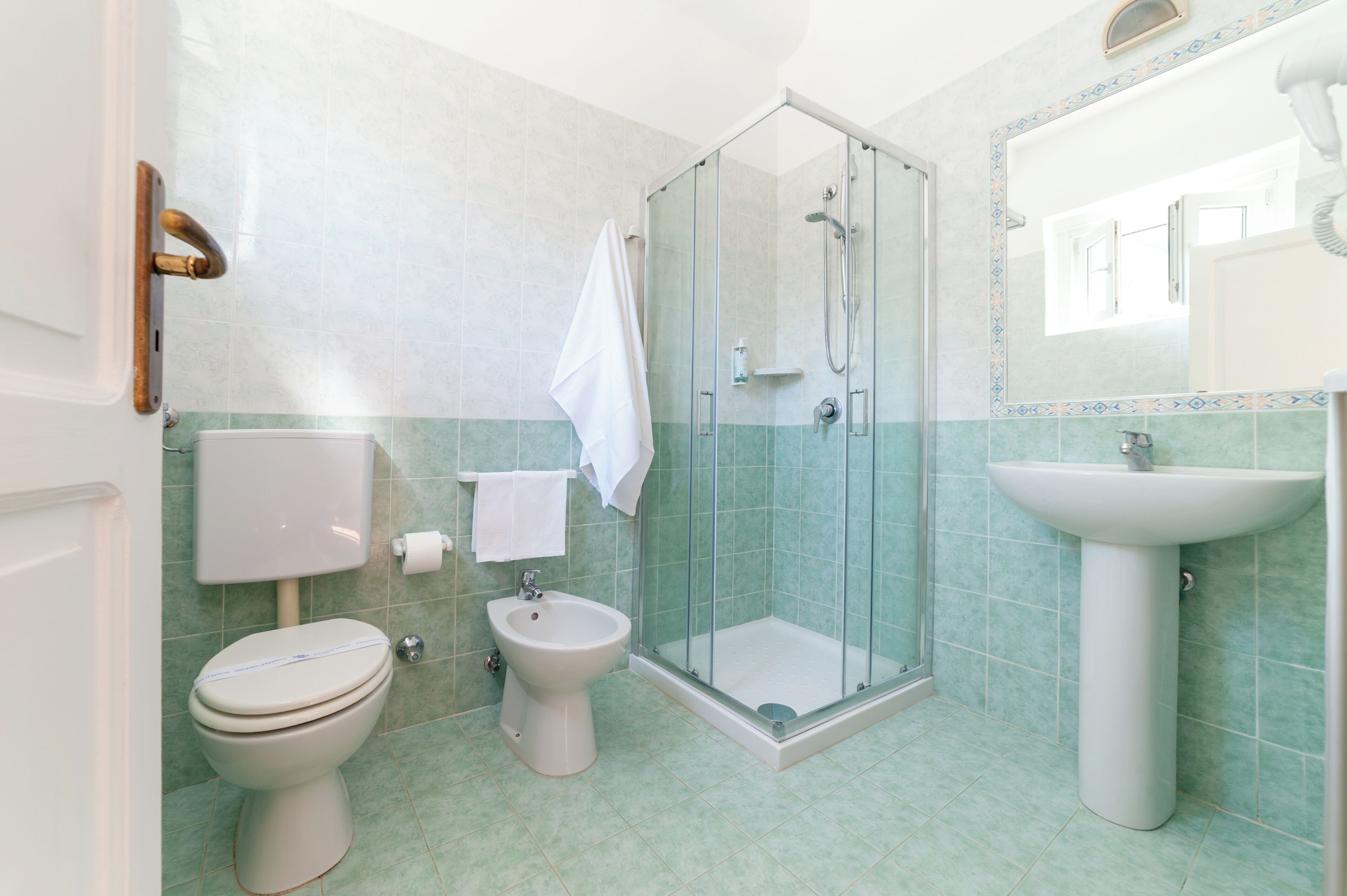 Een badkamer met toilet, bidet, douche en wastafel.