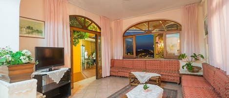 Una sala de estar acogedora con televisión, sofá y vistas al exterior.