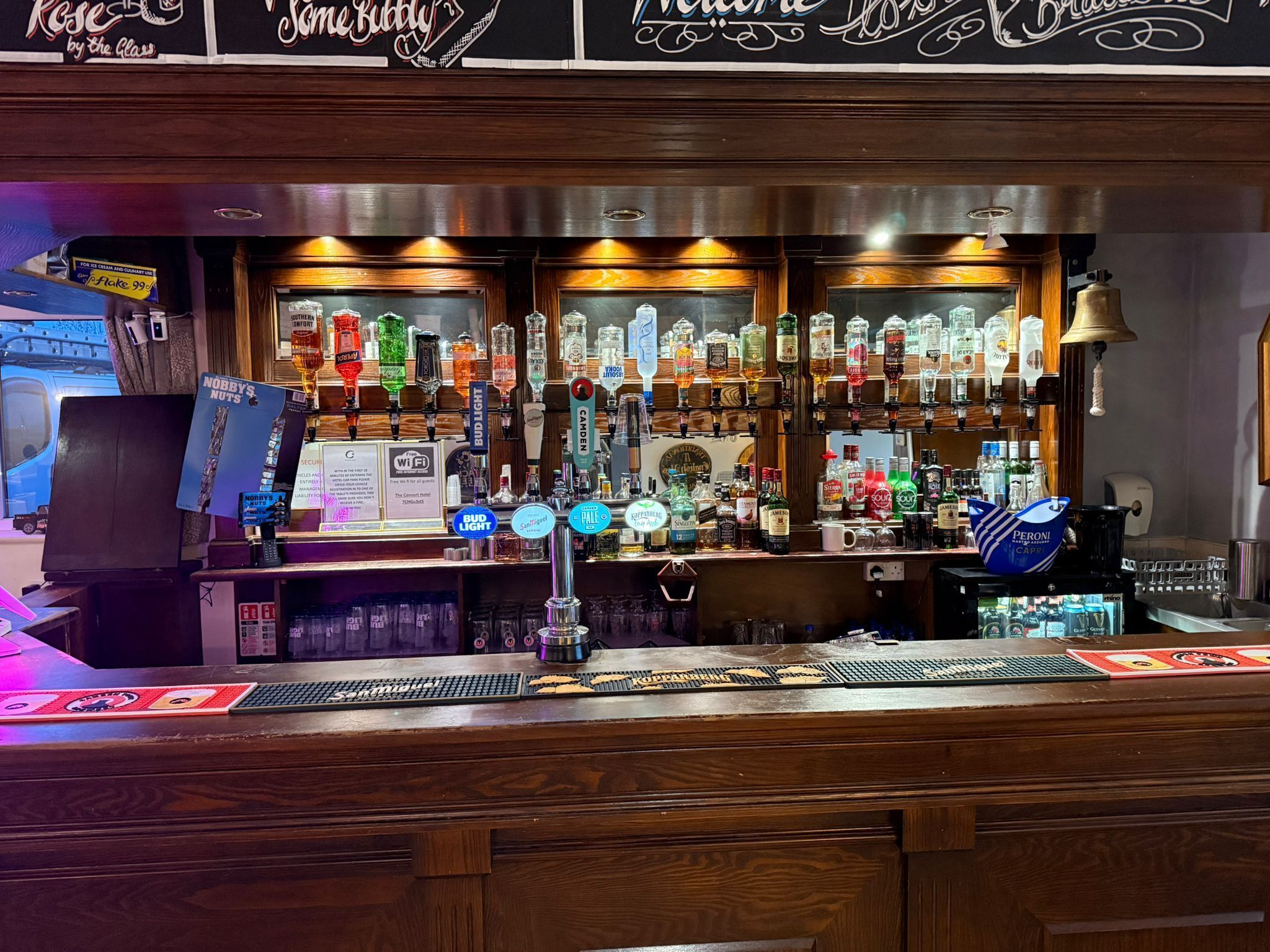 A bar area with multiple liquor bottles, a beer tap, and a coffee machine.