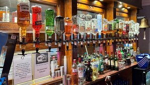 A bar area with various liquor bottles, glasses, and a sign offering free Wi-Fi. - Consort Hotel & Urban Spa (Rotherham)