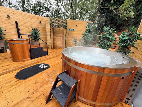 A wooden deck with a hot tub, a wooden bench, and a small table.