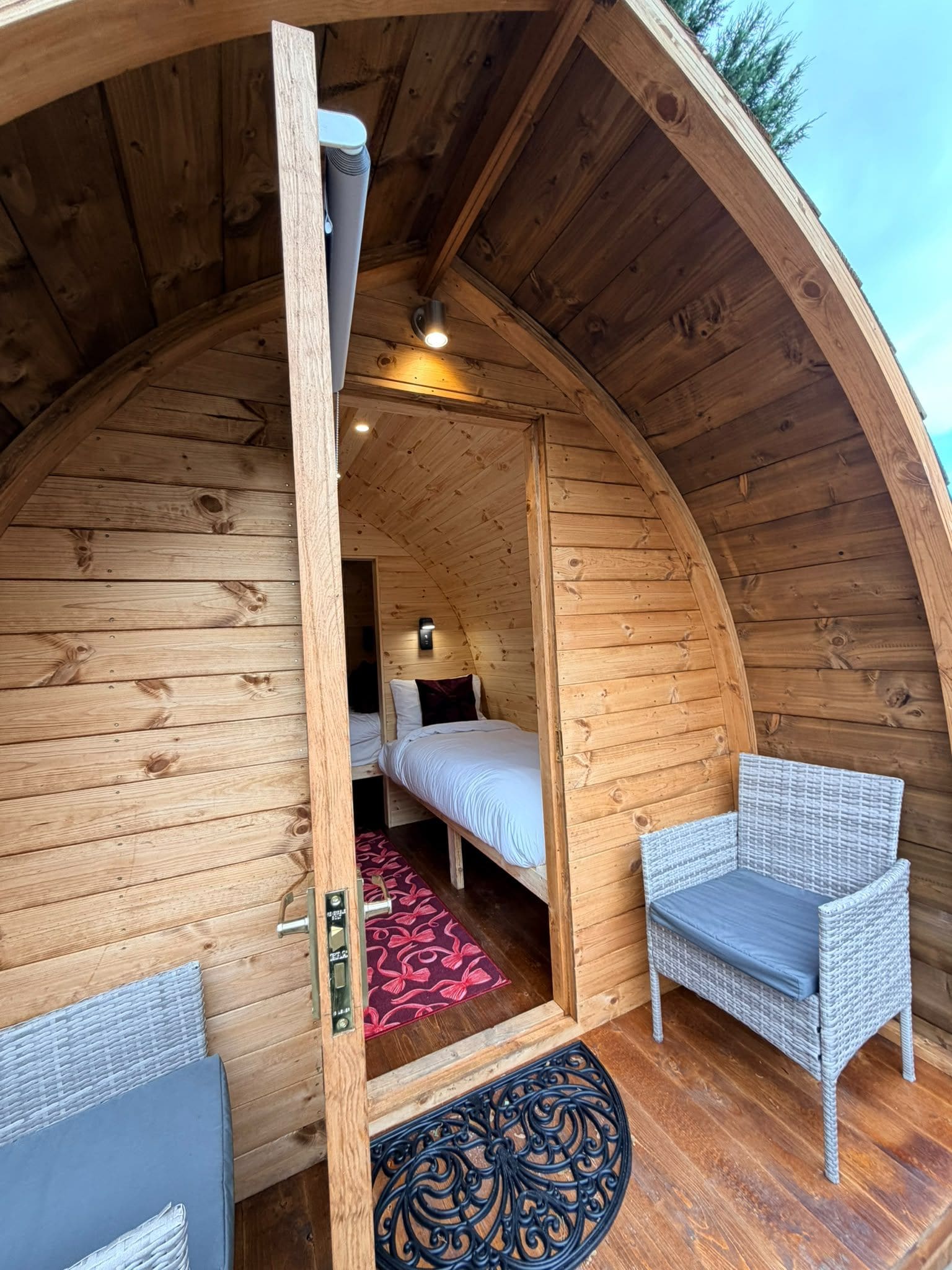 A cozy, wooden interior with a bed, two chairs, and a small table.