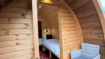 A cozy, wooden interior with a bed, two chairs, and a small table.