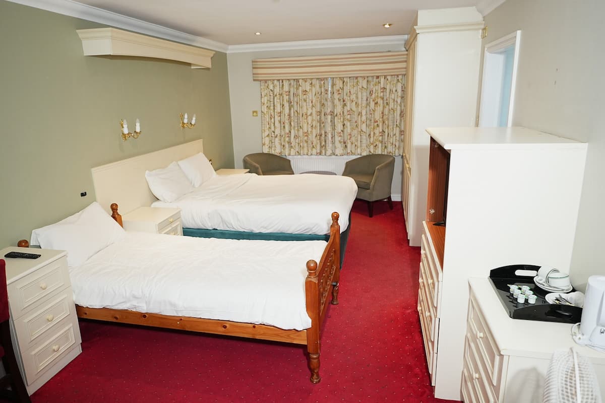 A hotel room with two beds, a desk, a chair, a telephone, and a minibar.