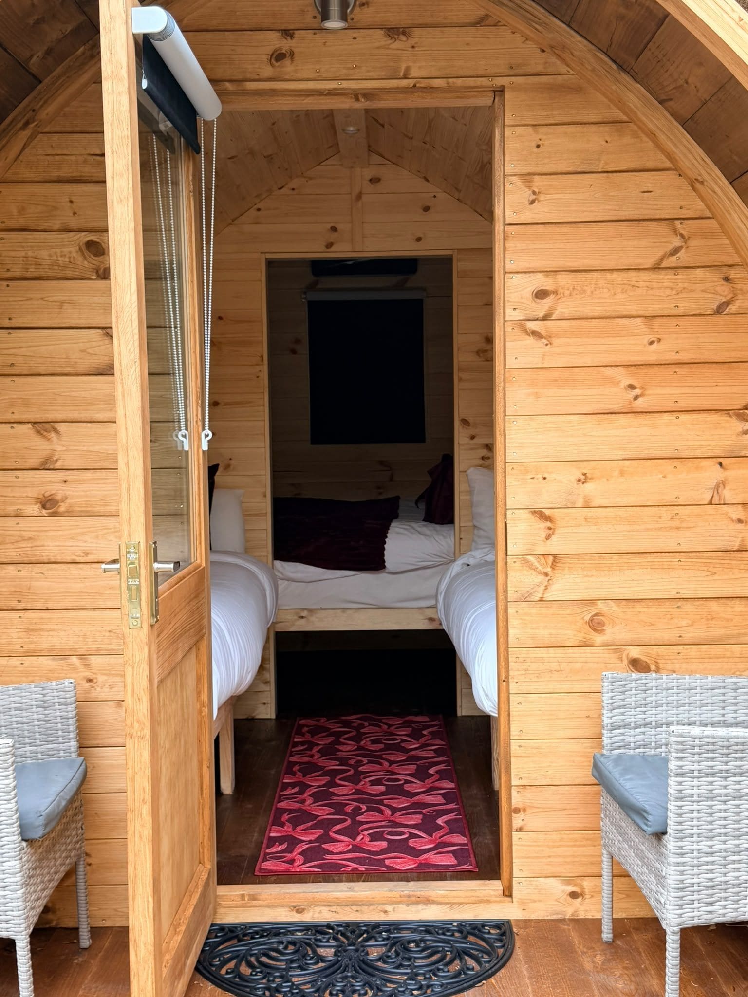 A cozy wooden cabin room with a bed, two chairs, and a patterned rug.